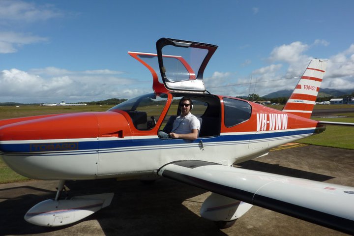 L'auteur posant dans un avion Tobago rouge et blanc , dont l'immatriculation est VH-WWW